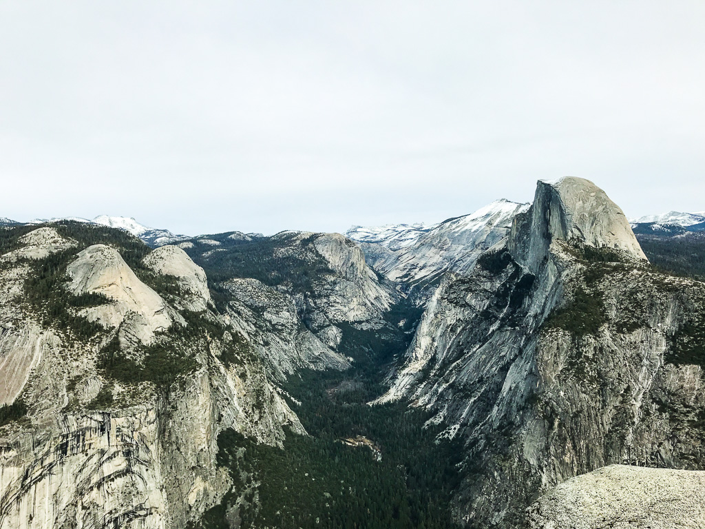 A wide view of rugged mountain cliffs and green valleys under a cloudy sky.