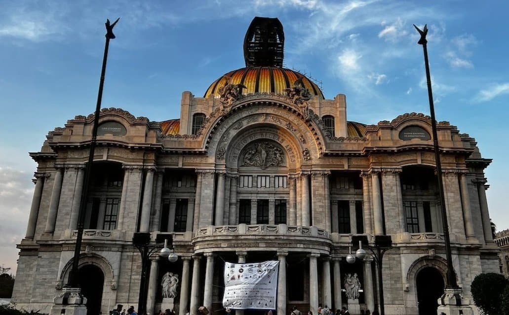 Front view of the Palacio de Bellas Artes in Mexico City with a banner held up in front of the entrance.