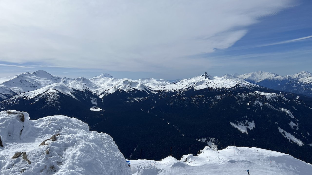 Snow-covered mountains near Vancouver, perfect for nature seekers and day trips from Vancouver, with skiers on forested slopes below.