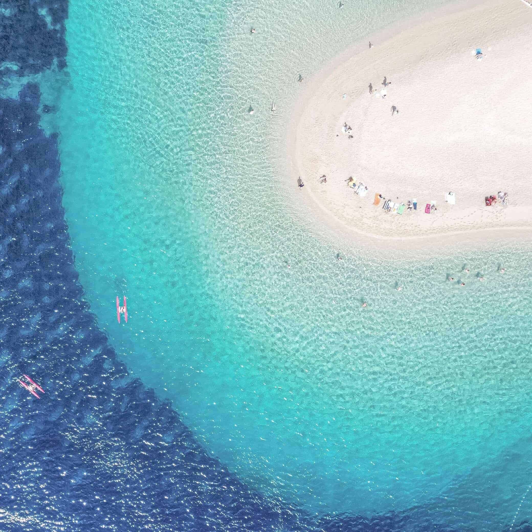 An aerial view of a beach and different shades of blue at a beach in Croatia.