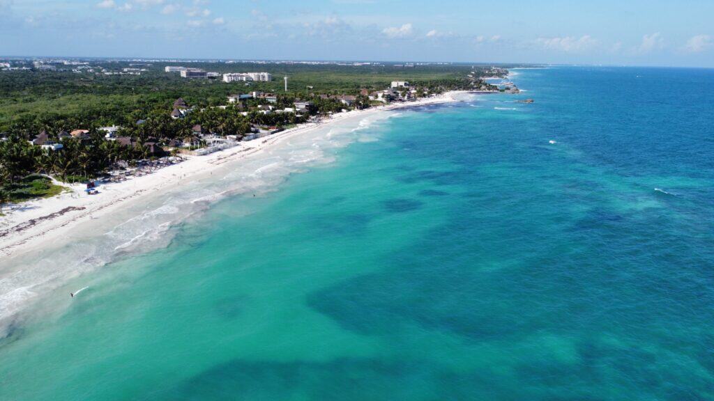 Aerial view of Tulum coastline with turquoise water, white beach, and lush trees—perfect for your Tulum Travel Guide adventure.