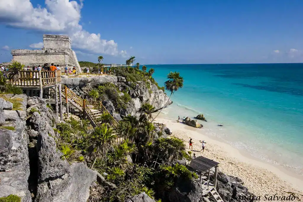 Ancient stone ruins in Tulum overlook a sandy beach and turquoise sea, offering a perfect scene for any Tulum travel guide.