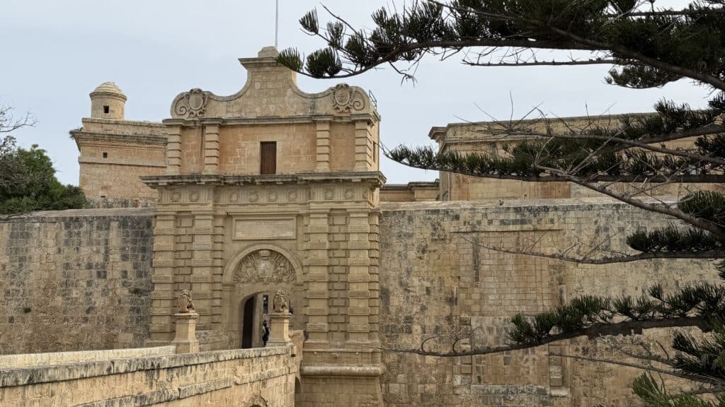 Arched stone entrance of a historic fort with ornate carvings, a stunning spot to include on your 3 day Malta itinerary.