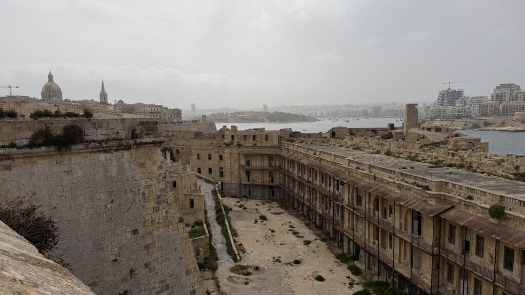 View of an old fort with weathered stone walls, perfect for your Malta travel or 3 day Malta itinerary, overlooking cityscape and waterfront.