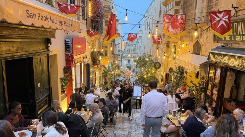 Outdoor diners fill a lively, decorated street in Malta—perfect for your 3 day Malta trip or to add to your Malta itinerary.