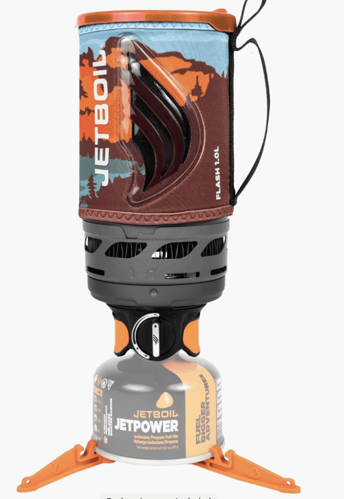 A Jetboil portable camping stove—essential backpacking gear with an orange base, black burner, and patterned insulated cooking cup.