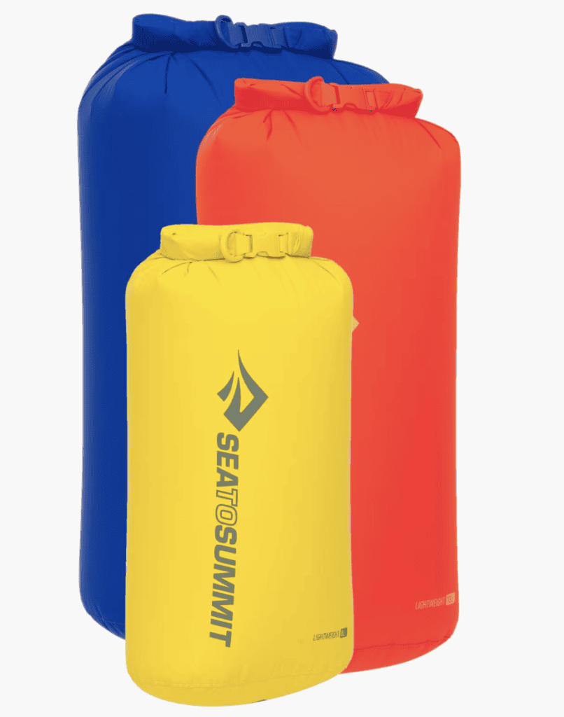 Three waterproof dry bags for hiking equipment stand upright; the yellow Sea to Summit bag is ideal for Pacific Crest Trail adventures.