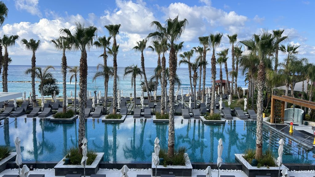 Infinity pool lined with palm trees facing the ocean, perfect for a Cyprus itinerary.
