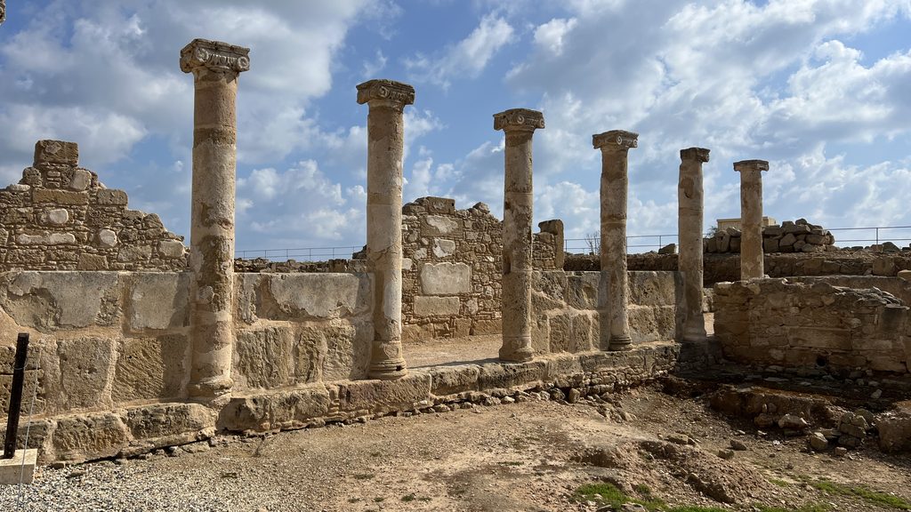 A row of ancient stone columns stands before ruined walls under a cloudy sky, a highlight for any Cyprus itinerary.
