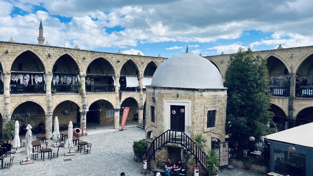 The Great Inn courtyard in Nicosia, a highlight of any Cyprus itinerary, featuring a central domed stone mosque and two-story arched galleries.