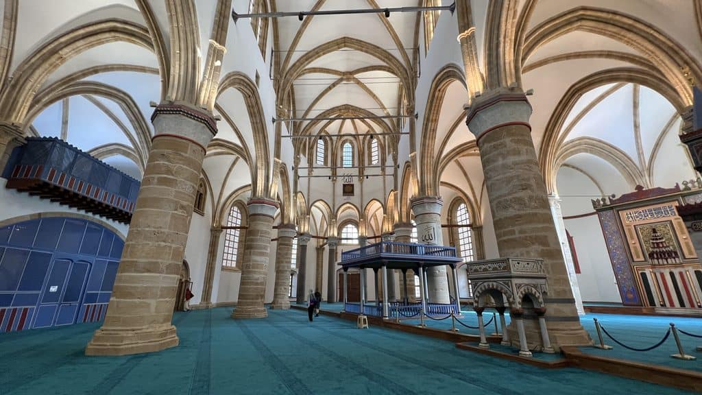 Interior of a historic mosque with stone columns, arched ceilings, and a green carpet, as seen on a 3 day Cyprus trip.